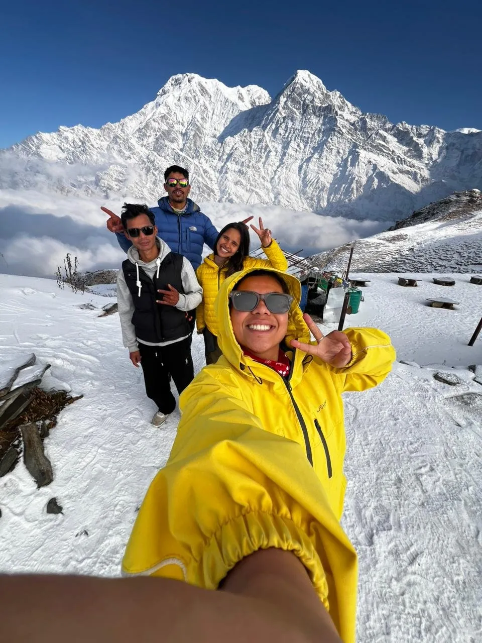 Guide Pratikshya Khanal and a group of trekkers on fresh snow high on the Mardi ridge, Annapurna South and Machhapuchhre filling the sky behind them.